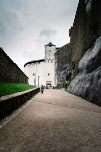 Man walking on road along buildings