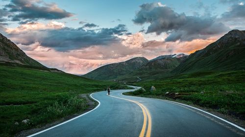 Road leading towards mountains against sky