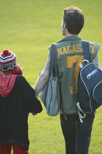Rear view of man with boy walking on field