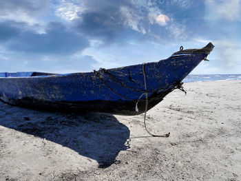 Sailboat moored on beach against sky