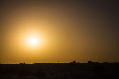 Scenic view of silhouette field against orange sky