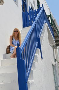 Low angle view of woman sitting on steps by railing