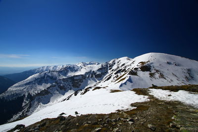 Scenic view of snowcapped mountains against clear blue sky