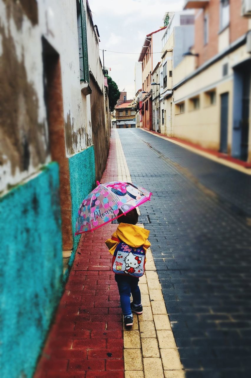 built structure, architecture, building exterior, street, real people, one person, women, city, day, lifestyles, full length, the way forward, rear view, footpath, transportation, wall, incidental people, direction, walking, outdoors