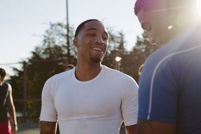 Happy male friends standing at basketball court