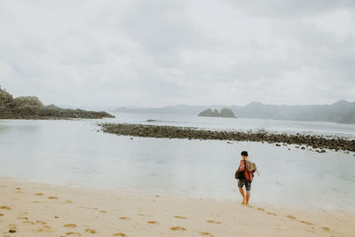 Rear view of man on beach against sky