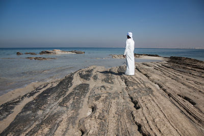 Man with umbrella on beach against clear sky