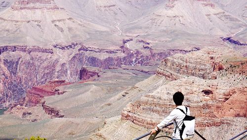 Man standing on grand canyon skywalk against rocky mountains