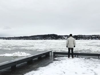 Rear view of man standing by sea against sky