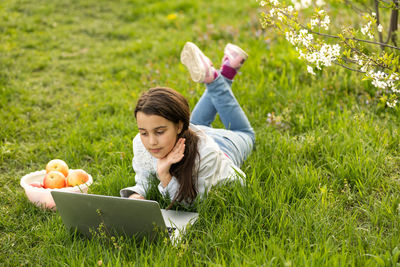 Little girl using laptop computer in a backyard. child studying 