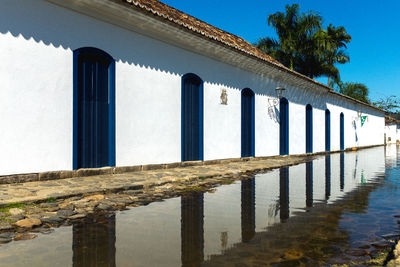 Built structure by sea against clear blue sky