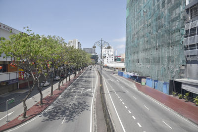 Road by buildings in city against sky