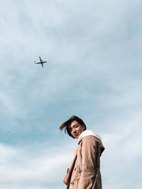 Low angle view of airplane flying against sky and girl