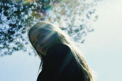 Low angle portrait of woman against sky