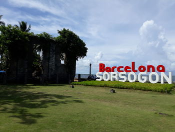 Information sign on field against sky