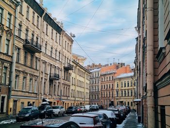 Cars on street amidst buildings in city against sky