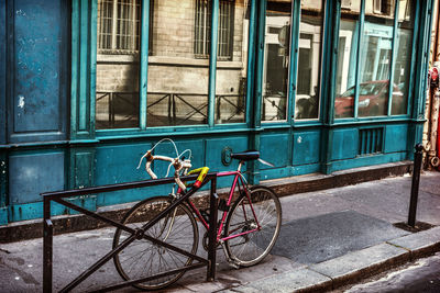 Bicycle parked on footpath against building