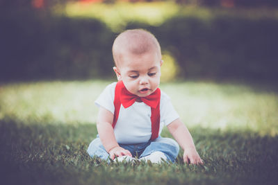 Cute boy sitting on grassy field