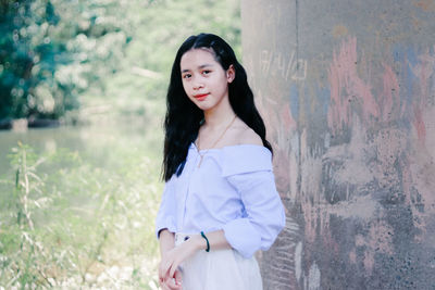 Portrait of beautiful woman standing against wall