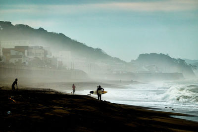 People on beach by mountain against sky