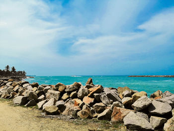 Rocks on shore by sea against sky