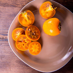 Persimmon cut into halves on a plate on a wooden table,copy space,closeup