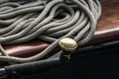 High angle view of golden metal against rope on boat