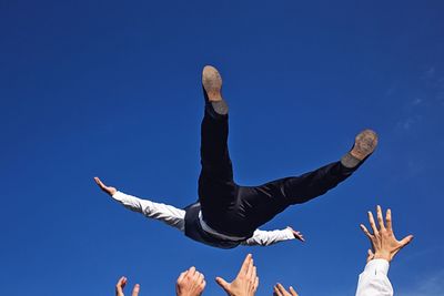 Low angle view of woman standing against clear blue sky