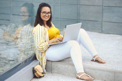 Young woman using laptop while sitting on floor