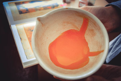 Close-up of hand holding tea cup on table