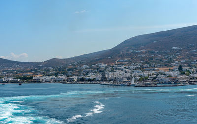 Sea by buildings against blue sky