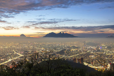 High angle view of illuminated city against sky at sunset