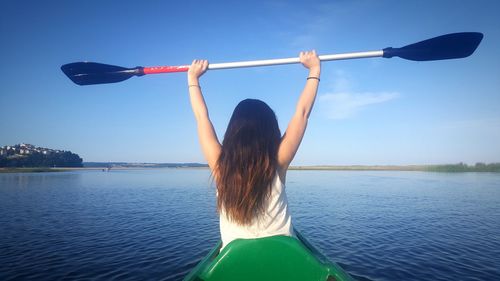 Rear view of woman canoeing on river