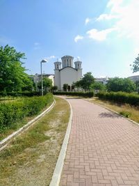 Footpath amidst buildings against sky