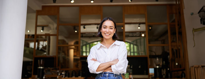 Portrait of young woman standing against window