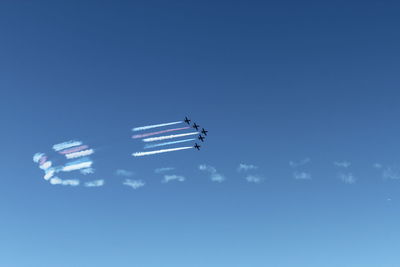 Low angle view of airplane flying against blue sky