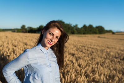 Portrait of smiling young woman standing in field