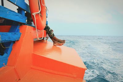 Low section of man standing on beach against sky