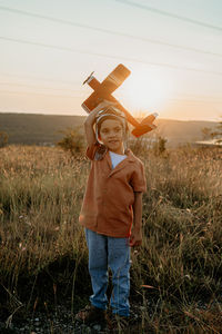 Young woman with arms raised standing on field