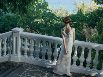 Woman standing by railing against trees