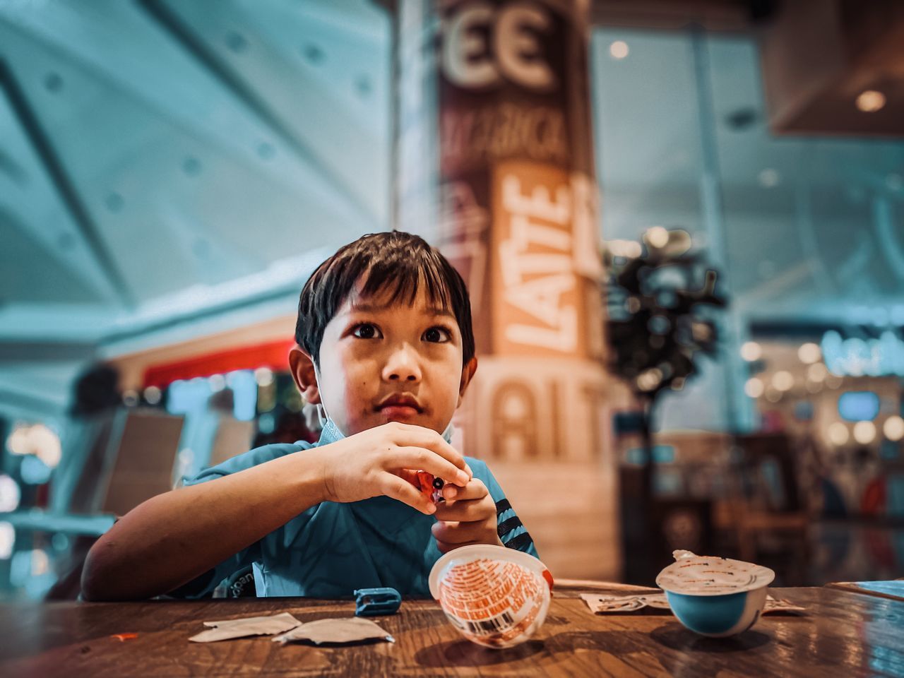 PORTRAIT OF BOY EATING ICE CREAM IN RESTAURANT