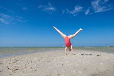 Woman with umbrella on beach against sky