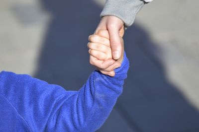 Cropped image of mother and child holding hands outdoors