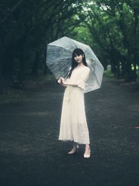 Woman standing with umbrella in rain