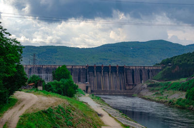 Scenic view of dam and mountains against sky