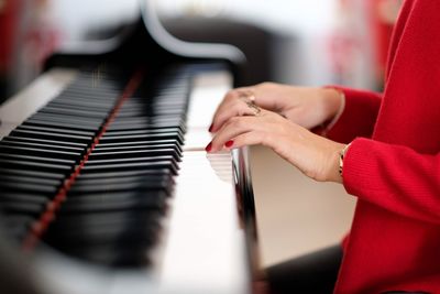 Midsection of woman playing grand piano