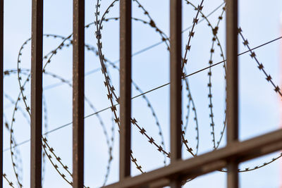 Low angle view of metal fence against sky