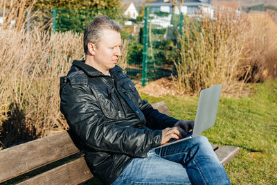 Young man using laptop while sitting on bench