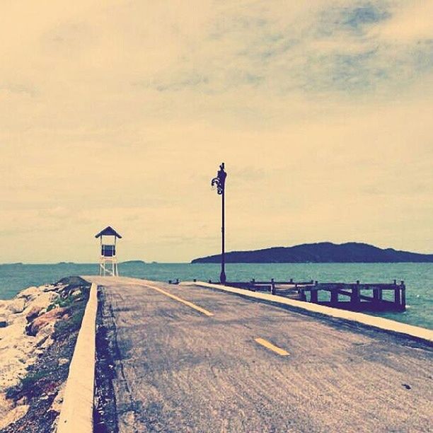 sky, the way forward, guidance, sea, cloud - sky, lighthouse, tranquility, direction, water, tranquil scene, cloud, nature, street light, road, scenics, transportation, beauty in nature, outdoors, cloudy, horizon over water