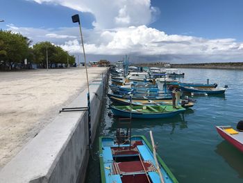 Boats moored at harbor against sky